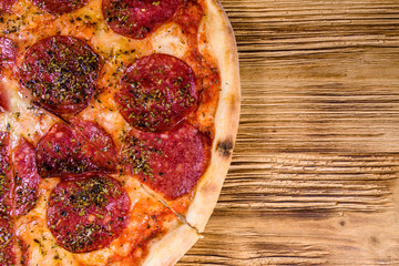 Pizza with salami sausage and parmesan cheese on a wooden table. Top view