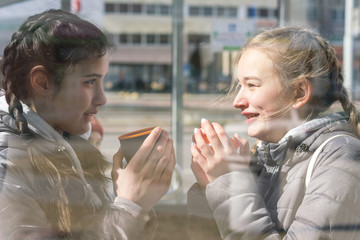girlfriends communicate and drink hot tea or coffee