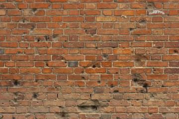 Old red brick wall with bullet holes