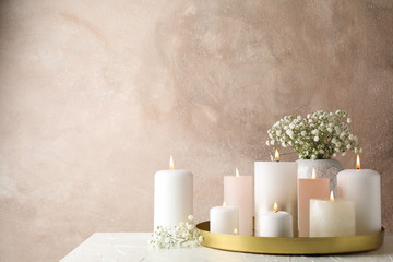 Burning candles, tray and flower on white table, space for text