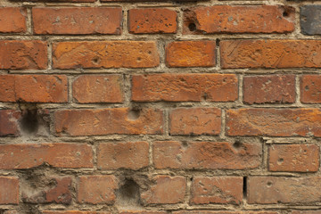 Old red brick wall with bullet holes. Close up