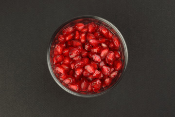 Red Pomegranate seed in glass on black paper background
