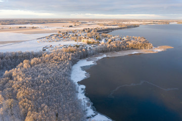 Aerial drone view of a lake coast starting to freeze over in winter sunrise light. Tartu, Estonia.