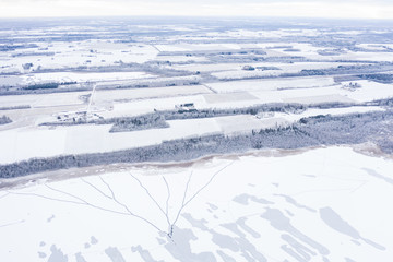 Fototapeta na wymiar Aerial drone view of a partially frozen lake with unfrozen patches and ice cracks on a winter morning. Tartu, Estonia.