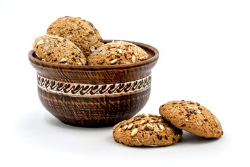 Clay deep plate and oatmeal delicious, healthy cookies with sunflower seeds on a white isolated background_