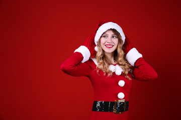 Studio shot of beautiful smiling young woman wearing sexy santa claus suit for Christmas. Attractive blonde female in tight red dress, new years eve. Copy space, isolated background, close up.