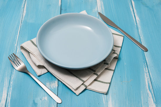 Blue Plate With Utensils And Dish Towel On Blue Wooden Background With Perspective