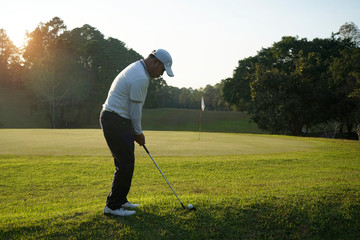 Fototapeta premium Blurred golfer playing golf in the evening golf course, on sun set evening time.