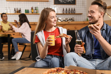 Young couple eating delicious pizza in cafe