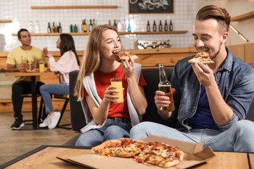 Young couple eating delicious pizza in cafe