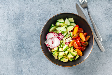 Vegan buddha bowl. Healthy vegetarian salad with cherry tomatoes, cucumber, radish,, avocado and lettuce.
