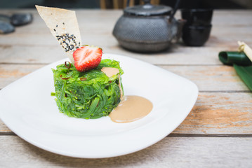 Traditional oriental seaweed salad with peanut sauce on a wooden table in a restaurant.