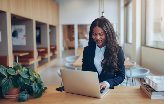 Smiling African American businesswoman using her laptop at a tab