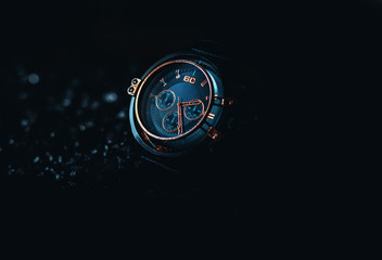 A metallic gold Blue men's watch on a black background. 