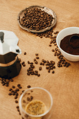 Roasted coffee beans, grounded coffee, geyser maker - alternative coffee brewing process. Coffee maker, aromatic beans and espresso in glass cup on wooden table