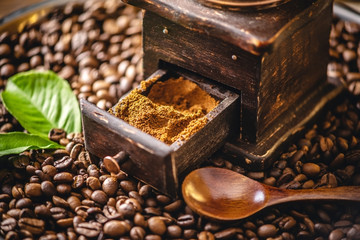Wooden vintage hand coffee grinder and mug on a pile of brown coffee beans. Grinding fragrant...