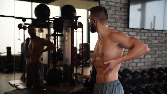 Ripped Athletic Nerd Flexing In Front Of A Mirror In The Gym