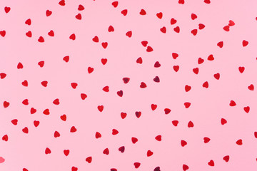 Red heart shape confetti pattern on light pink background. Valentine, love, wedding concept. Top view, flat lay
