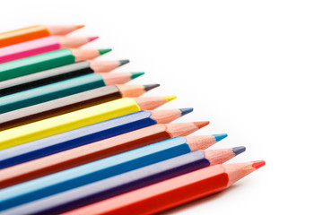 Fototapeta premium Colored pencils in a row on a white background, free space for text.