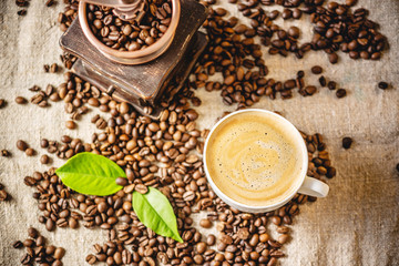 Cup of coffee with foam and a wooden vintage coffee grinder. Fragrant invigorating drink from freshly roasted beans.