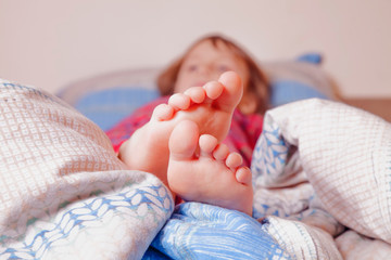  Sleep and relax concept. Beautiful groomed bare feet of cute little child girl in the bed.