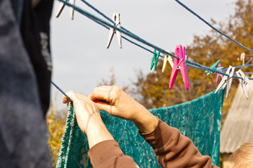 Laundry woman hangs clean wet cloth on clothes dryer after washing at home. Household chores and housekeeping.