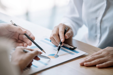 Fototapeta premium Business people gather to analyze marketing and investment information and using pen pointing to financial data chart at meeting.