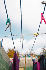 A clothespin hangs on the washing line. A rope with clean linen and clothes outdoors on the day of the laundry. Against the background of green nature and sky.