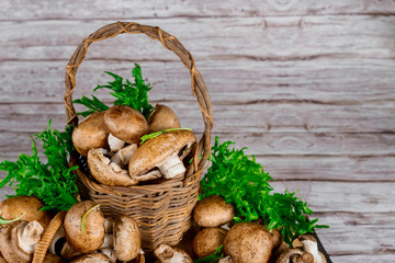 Brown portobello mushrooms in wicker wooden basket with grass decoration.