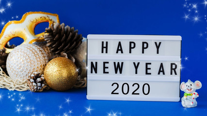 Happy New Year 2020 text on light box with little toy rat and Christmas toys and cones in mesh bag...