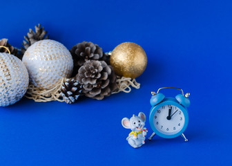 New year concept. Alarm clock, little rat, cones and Christmas toys on a blue background. 2020
