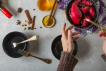 Blur book page. Boiled pears in mulled wine. Woman puts pears in a bowl.