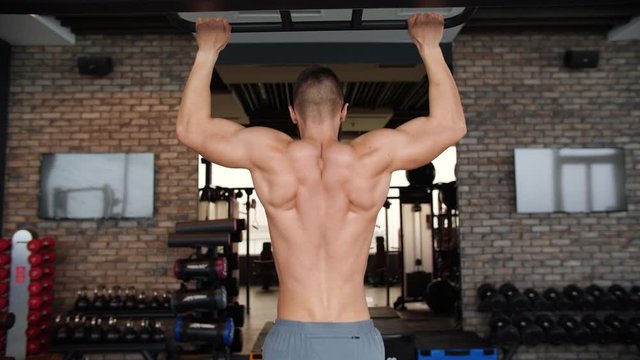 Ripped Shirtless Man Doing Pull-Ups in the Hardcore Gym