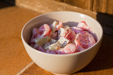 Fresh salad with tomato and cucumber, seasoned with sauce in a bowl at sunlight