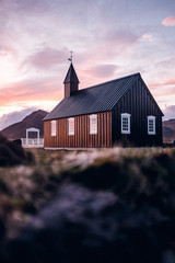 Kirche vor dramatischem Bergpanorama Island