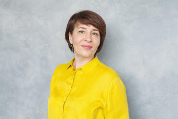 Happy middle aged business woman on gray background, portrait
