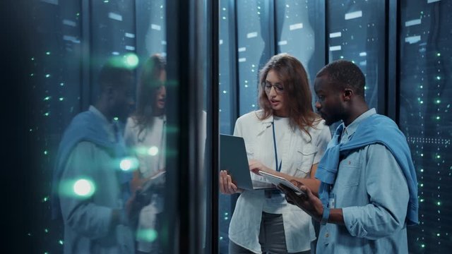 IT head administrator teaching young technician internet technologies in database. Diverse female and male server specialists coworking in server cabinet of cyberspace.
