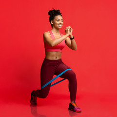 Cheerful afro fitness girl making working out with resistance band