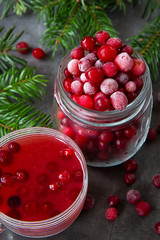 Frozen cranberry berry in a jar and cranberry juice in a glass on the table decorated with branches of the Christmas tree. Christmas winter time