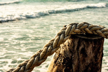 Fototapeta na wymiar Rope on a wooden pole used as barrier at the sea