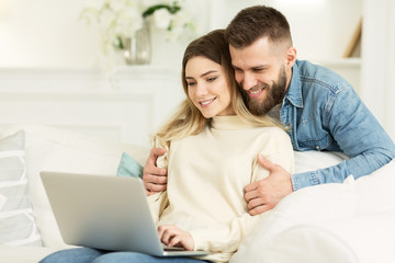 Loving couple browsing social media on laptop