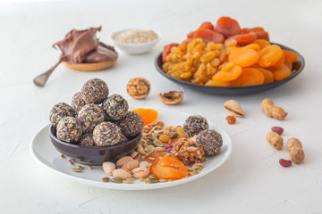 Natural healthy raw energy bites, chocolate paste and mix of dried fruits with nuts on a white table