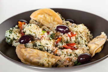 Healthy Quinoa Bulgur bowl with dumplings and black olives. Selective focus.