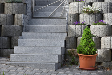 Garden staircase made of natural granite and a wall made of expanded clay concrete rings in a European city