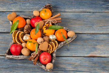 in a wicker vase in the shape of a star: tangerines, apples, walnuts, cinnamon, orange slices