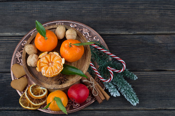 in a vase tangerines, apples, cinnamon, walnuts, candy staff and a branch of spruce