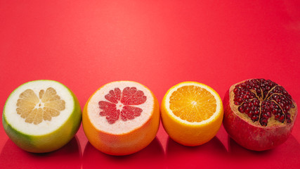 Juicy grapefruit, orange, pomegranate, citrus sweetie on red background.