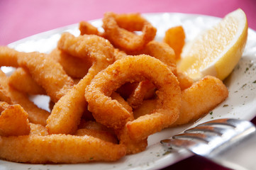 fried squid with lemon and fork on a plate
