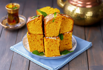 Lebanese dessert Sfouf. Traditional Middle Eastern semolina, almonds and turmeric cake, sliced and served on a plate with glass of mint tea.