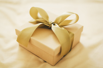 Fototapeta na wymiar Gift with golden ribbon on golden background